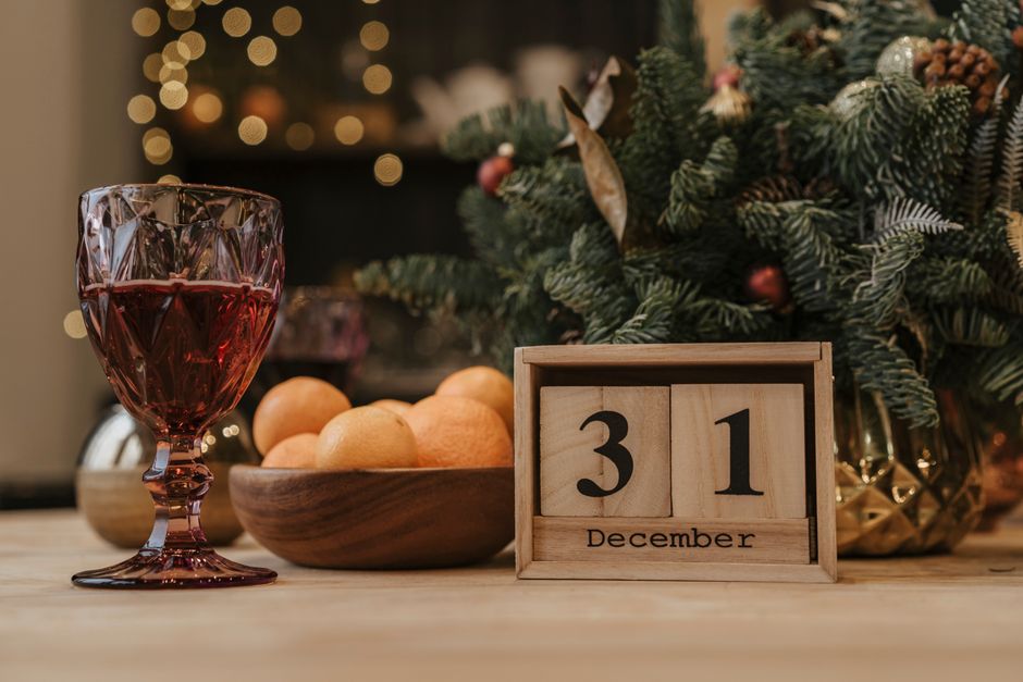 Festive New Year's Eve scene with a glass of red wine, December 31 calendar, and holiday decor.