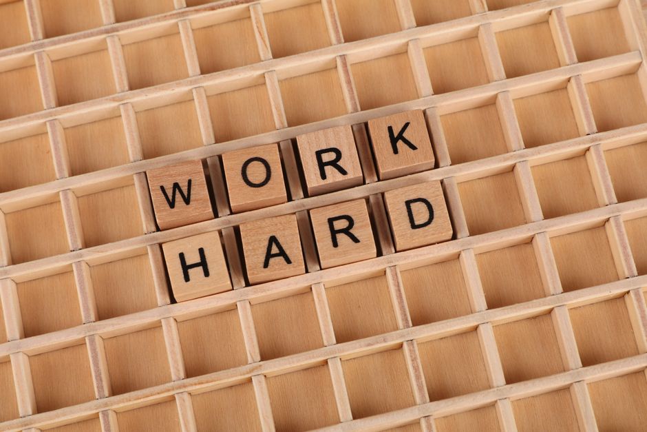 Creative wooden letter tiles forming the phrase 'work hard' on a grid. Perfect for motivation themes.