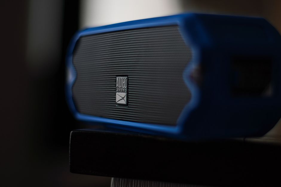 A modern blue Altec Lansing speaker with a sleek design on a black surface in focus.