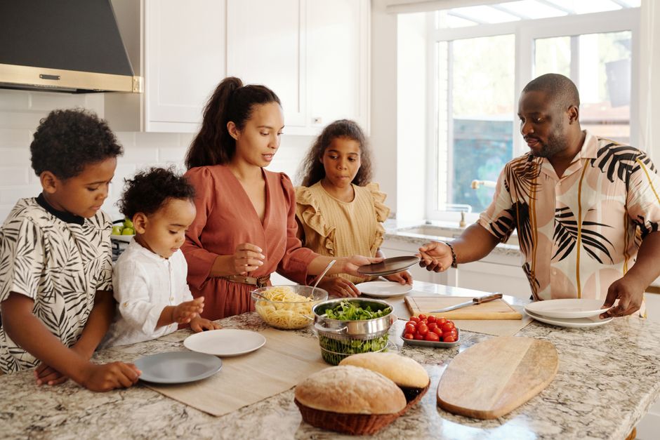 A family shares a joyful meal preparation in a bright, modern kitchen setting.