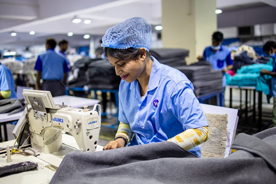 A dedicated textile worker operating a sewing machine in an industrial factory environment.