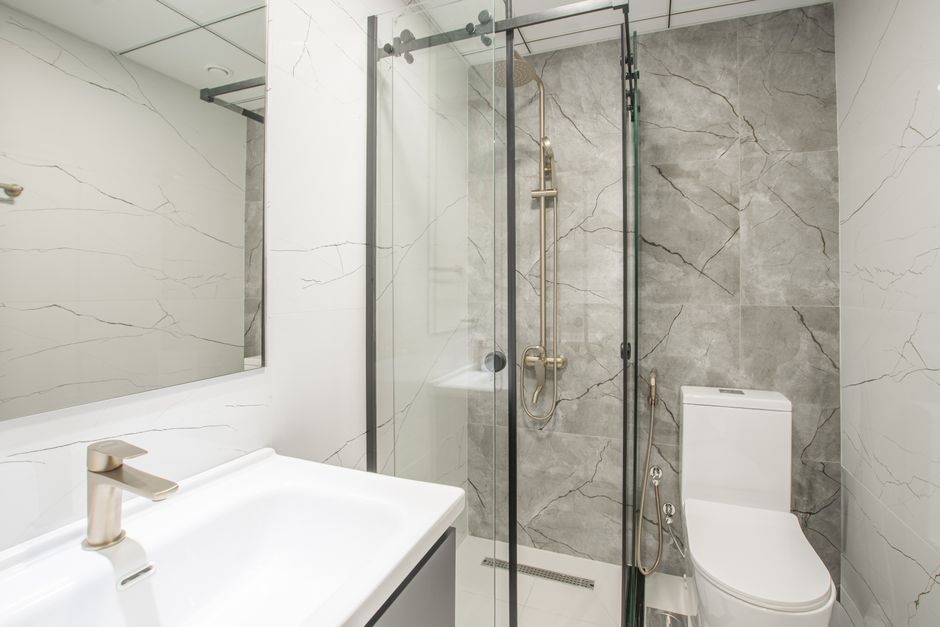 Bright modern bathroom featuring a glass shower, marble tiles, and sleek fixtures.