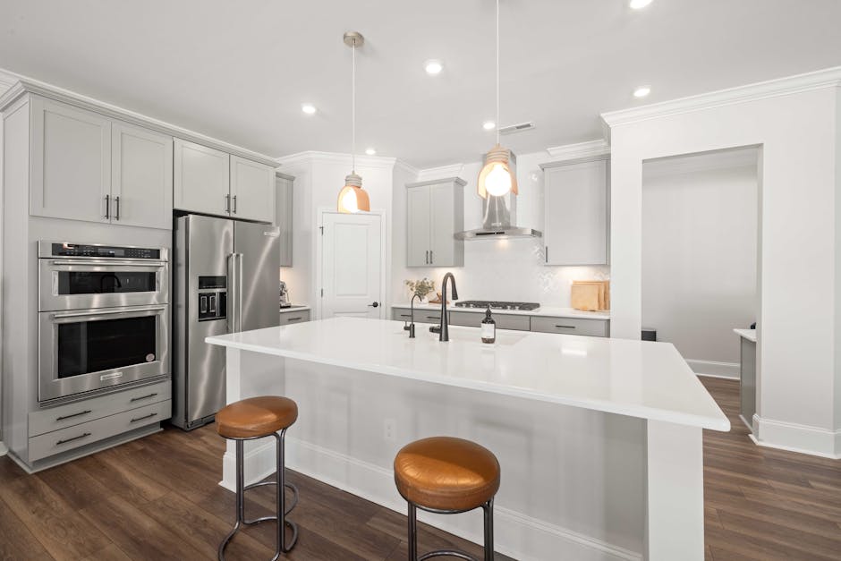 Sleek modern kitchen featuring a white island, stainless steel appliances, and stylish lighting.