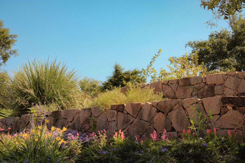 Serene garden featuring a stone terrace and vibrant flowers under a clear blue sky.