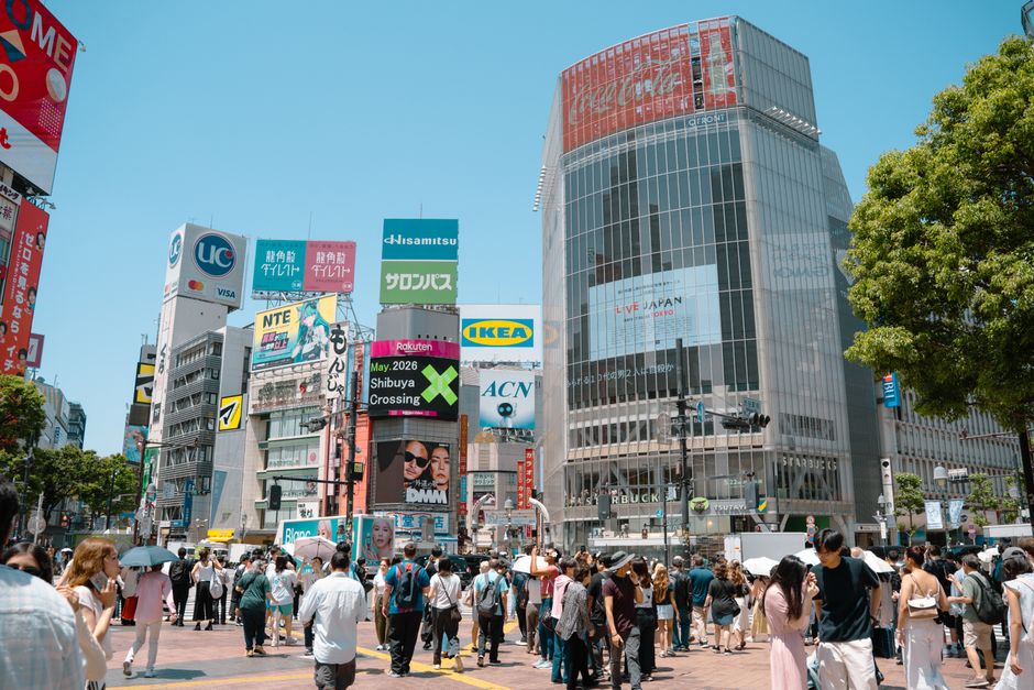A bustling scene at Shibuya Crossing in Tokyo, filled with diverse crowds and vibrant billboards.