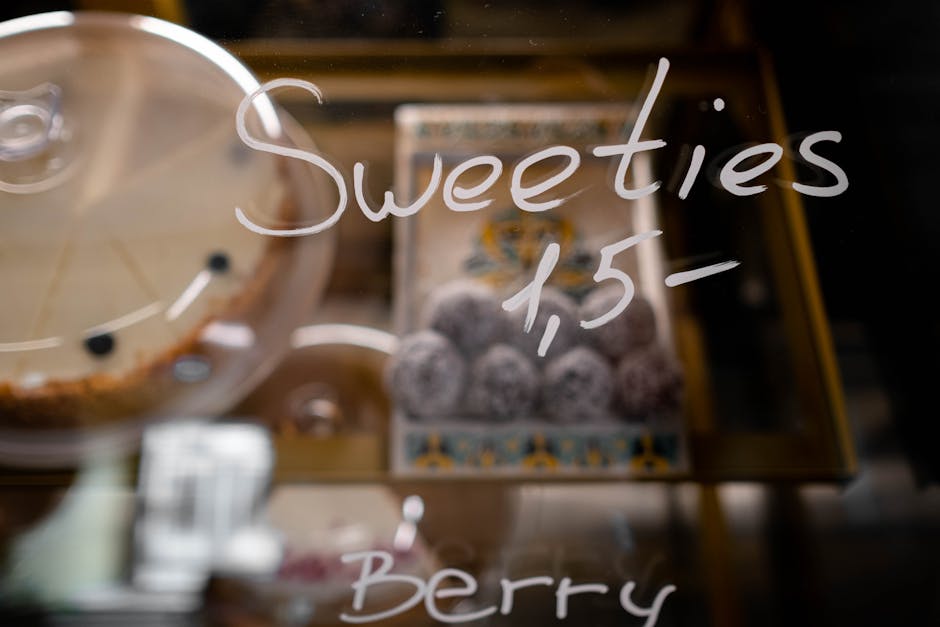 Glass display showing assorted sweet confections and cakes with price tag.