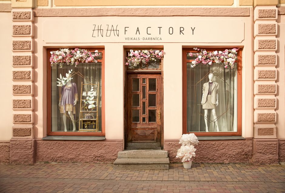 Charming storefront of Zig Zag Factory clothing store in Kuldīga, Latvia with floral decorations.
